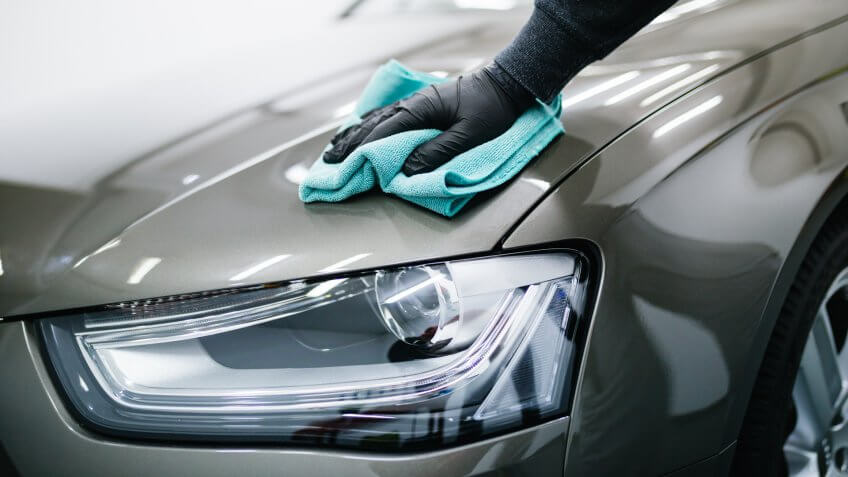 A man cleaning car with microfiber cloth, car detailing (or valeting) concept.