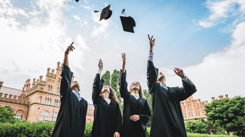 We've finally graduated!Graduates near university are throwing up hats in the air.