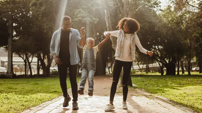 Happy beautiful family of three walking in park.