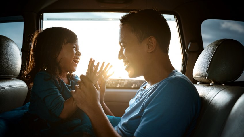 lovely asian daughter with father in the car playing together laughing.