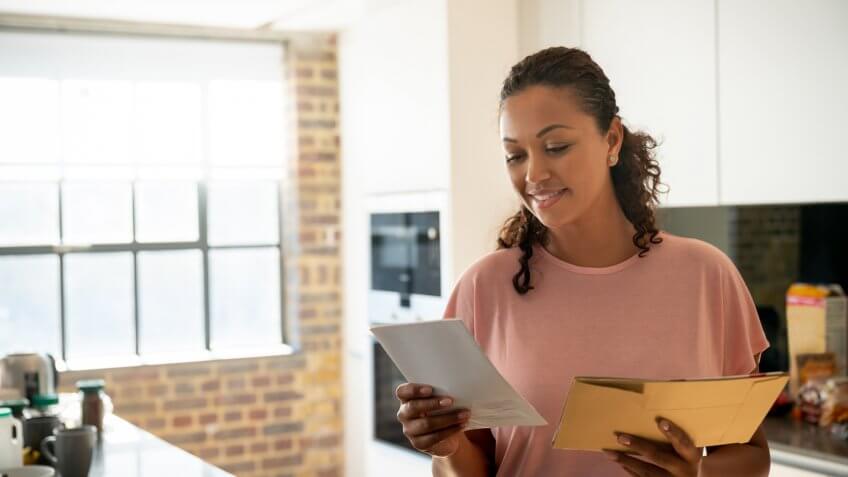Portrait of a happy woman reading her mail at home and smiling â lifestyle concepts.