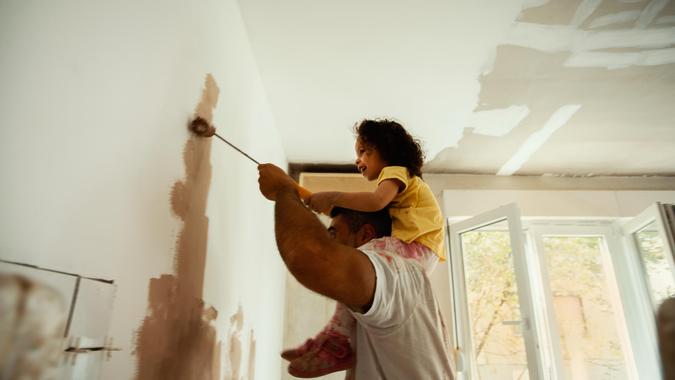 Young family renovating their home, painting wall.