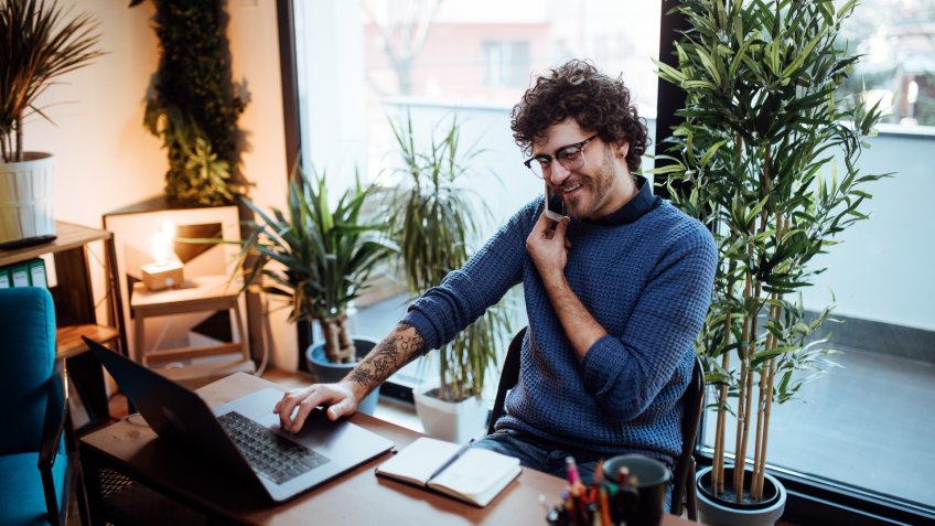 Young man talking on the phone in his home office.
