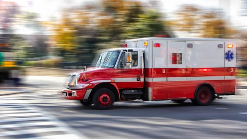 Photo of an red ambulance at a city street.