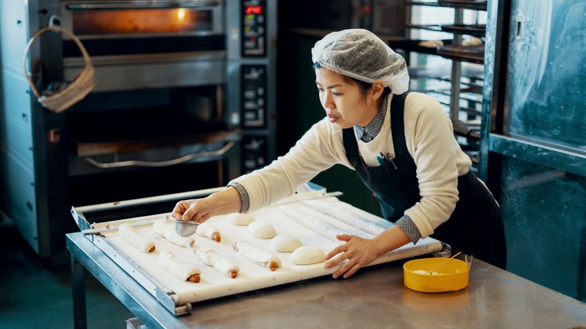 Mid adult woman baking bread in an industrial kitchen in Japan.