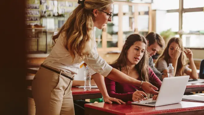 Female teacher talking to a student in classroom.