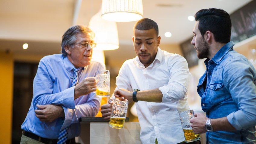 Three friends with beer in their hands cheering.