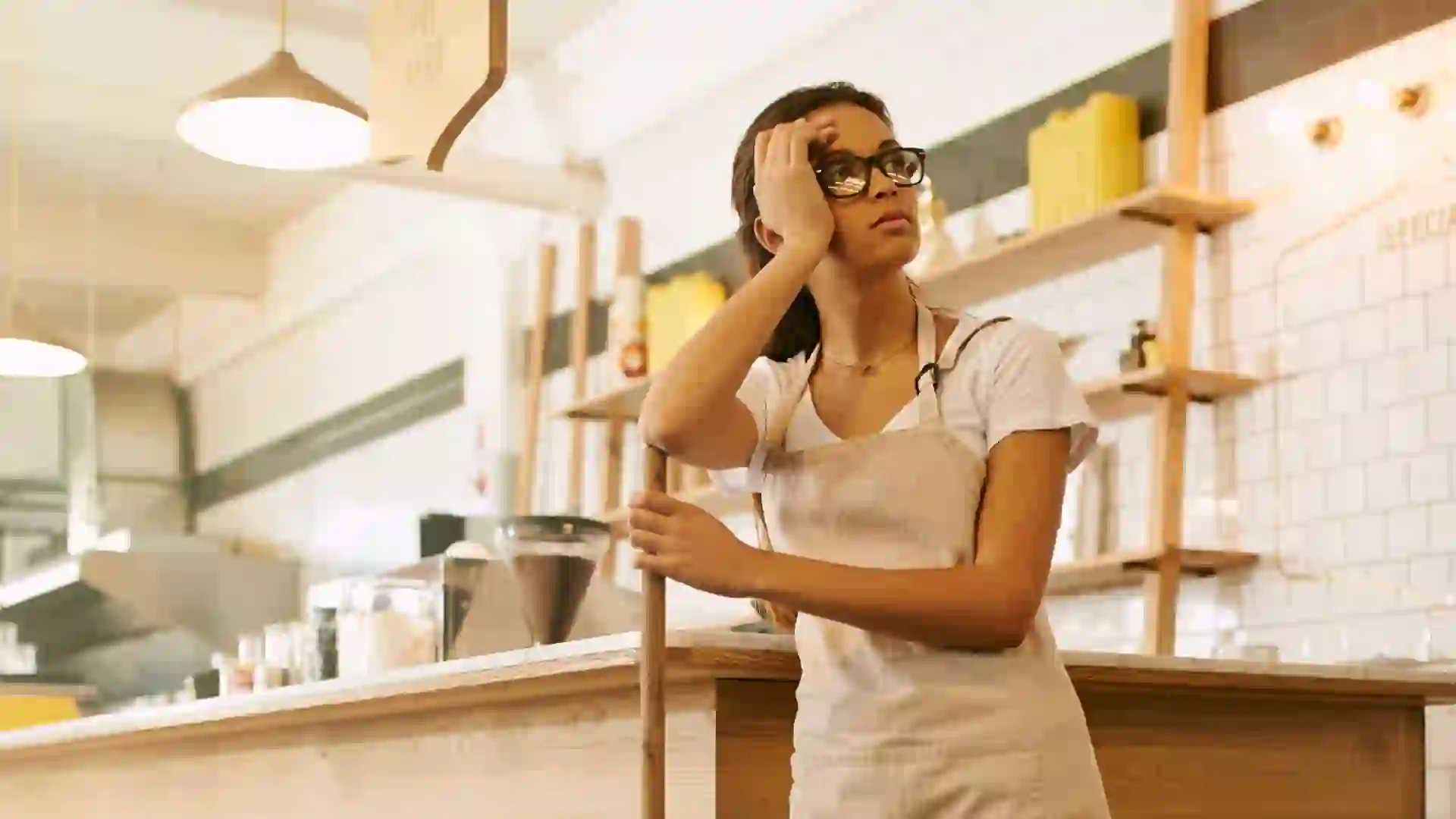 Shot of a young woman mopping the floor of a coffee shop during the day.