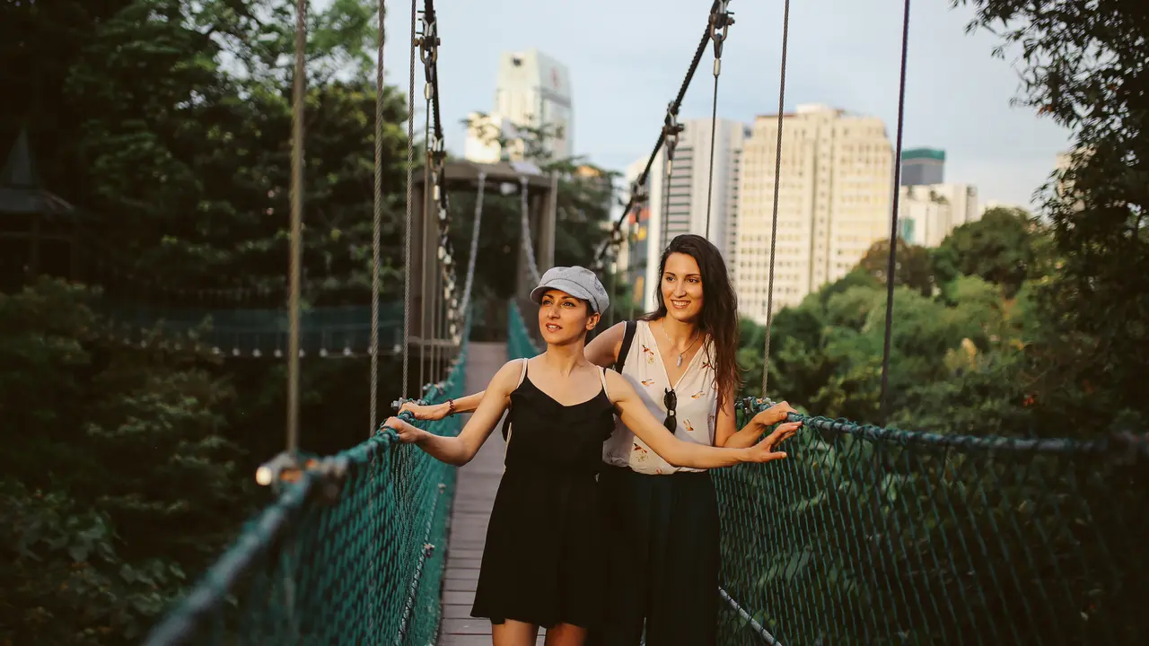Image of two young girl friends traveling together to Malaysia, enjoying a walk through the large city park in the center of Kuala Lumpur.
