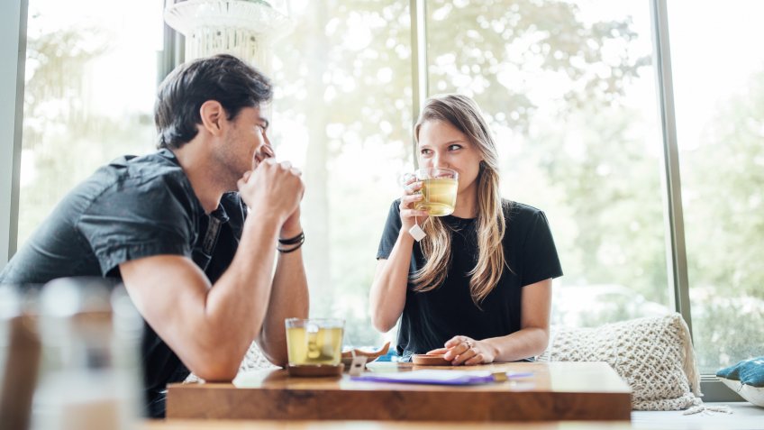 Young couple in love at cafe looking at each other and smiling.