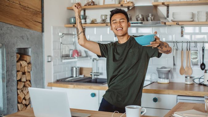 Young student prepare breakfast and dancing around table, he prepare for exams, classes are hard, he need to study more.