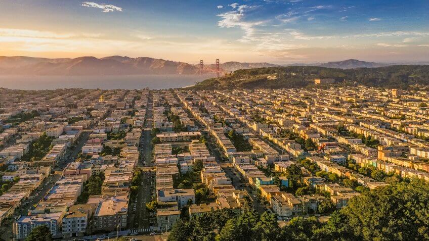 An aerial view from Golden Gate Park looking across the Avenues to the Presidio and Golden Gate Bridge just as the sun begins to set.