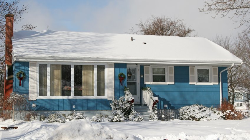 A small 1970's or late 60's bungalow decorated for Christmas and covered in snow.