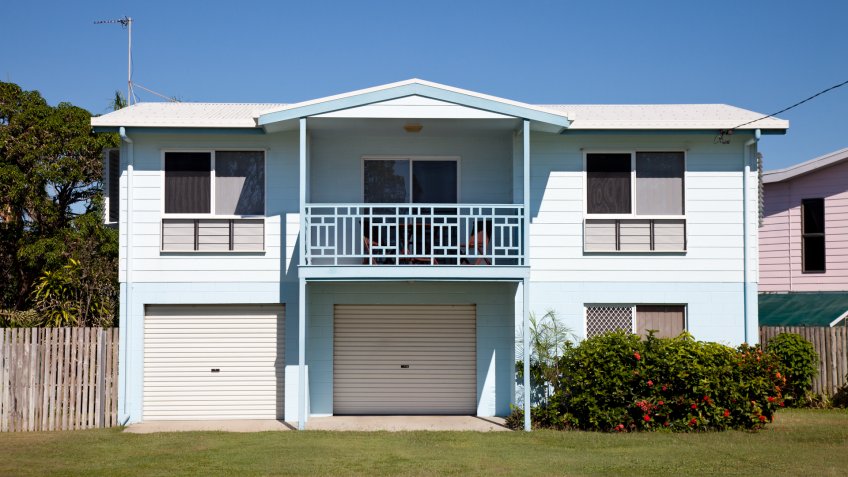 "Tidy two story basic Australian home built around the 1980aas, with blue sky and green grass.