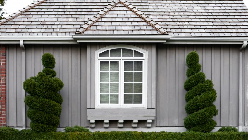 Centered view on the exterior of a craftsmen style home framed by spiral bushes, in a residential architectural background - Image.