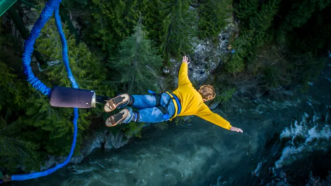 Young man bungee jumping over river.
