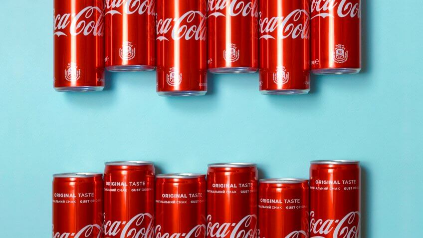 Flat lay shot carbonated red drink tin cans Coca Cola laying on pastel blue background - Image.