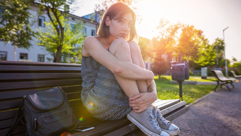 Beautiful young woman sitting alone in the park and thinking.