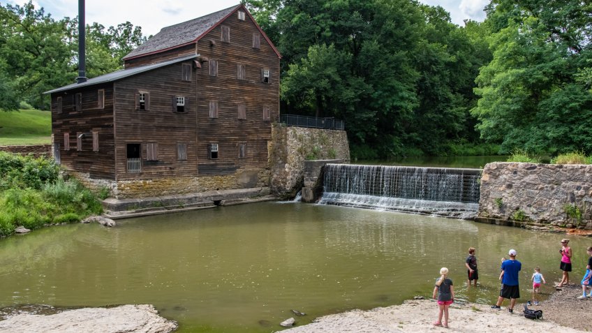 Muscatine County, Iowa/USA- July 18, 2018: A family looks across the water to the historic Pine Creek Gristmill build in 1848.