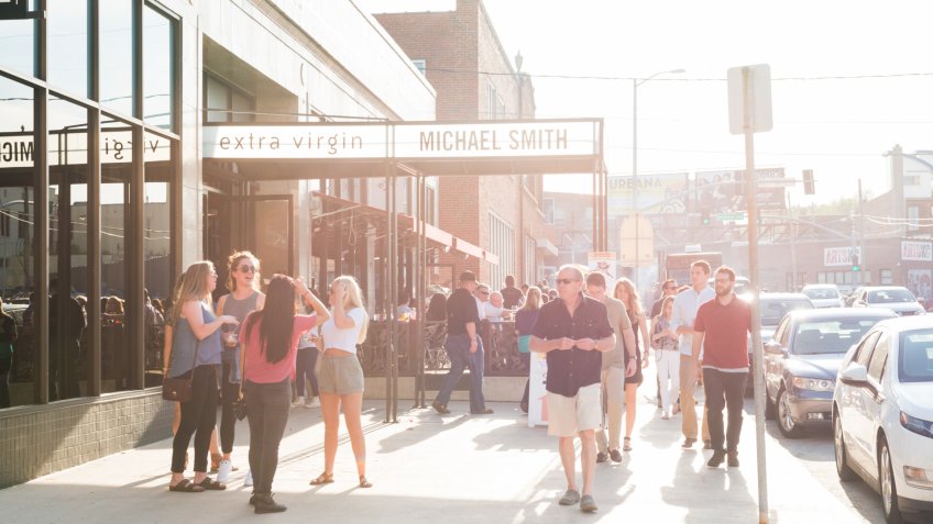Kansas City, United States - May 6, 2016: During the monthly Friday art walk on a warm spring afternoon, many people gather outside of a downtown restaurant as other people walk along the sidewalk.