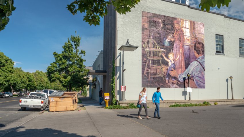 Logan, Utah, United States - August 31, 2018: Mural showing a traditional family with a couple passing by in the foreground taken in Logan, Utah.