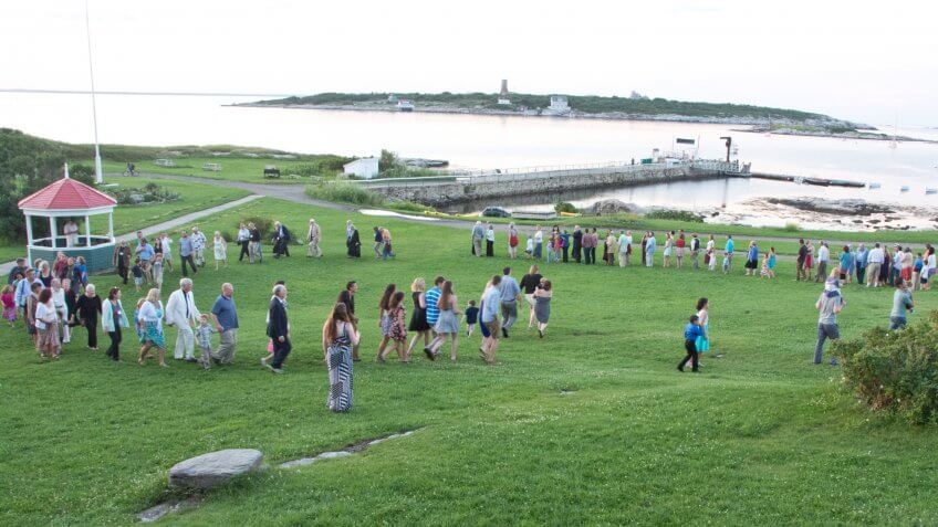 Rye, NH, USA - August 8, 2014: Visitors to Star Island join in a farewell dance called the Grand March on the grass near the Star Island dock on a summer evening.