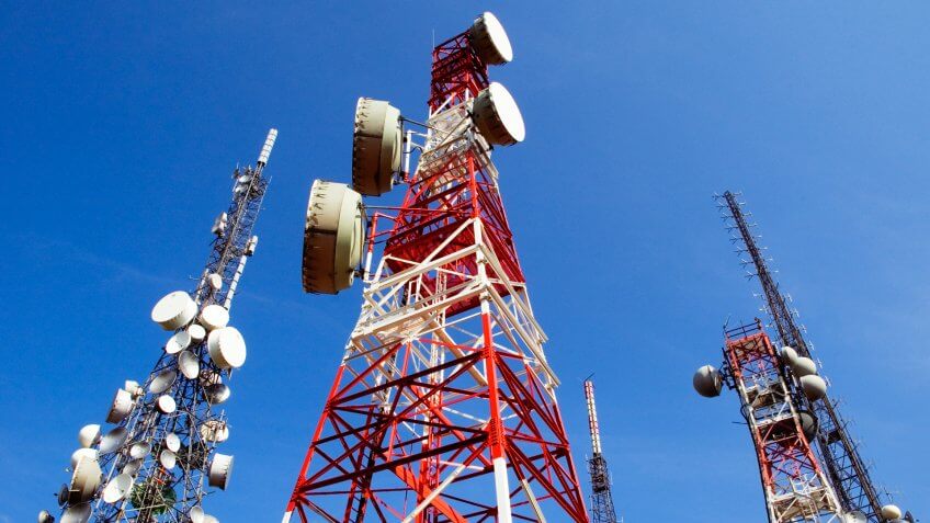 Telecommunications towers on blue sky, a red and white, the other white, antennas for television, radio, and mobile phones.