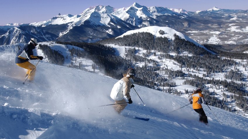 Skiers on Telluride's Gold Hill with the majestic Wilson Massif in the background.