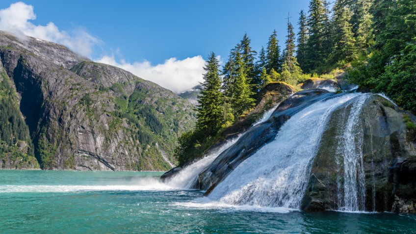 A waterfall cascades across smooth rock into the Tracy Arm Fjord in Alaska.