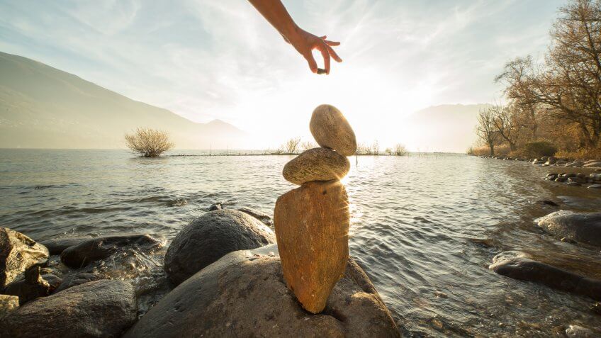 Detail of person stacking rocks by the lake.