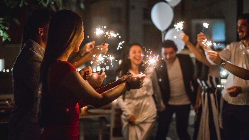 Just married couple showing up before their friends and running through the tunnel of sparklers.