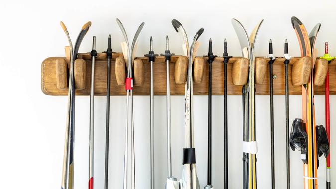 Lot of ski hanged on customized wooden wall mount at garage for seasonal storage.