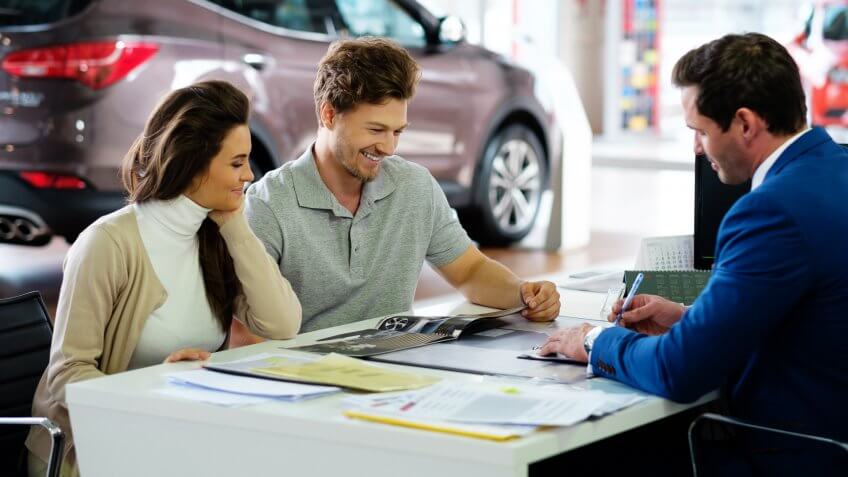 couple signing loan on their new used car