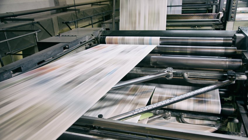Newspapers being printed in printing press.