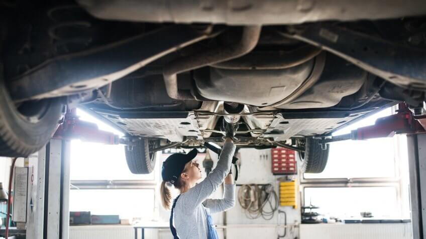 Female mechanic repairing a car.