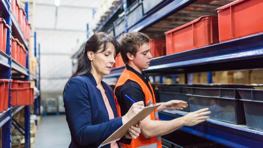 Store manager with warehouse worker checking stock levels.