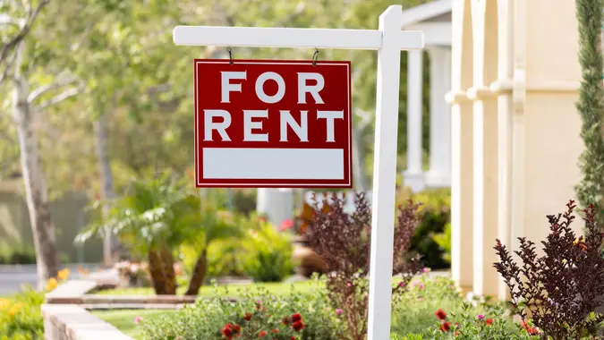 Red For Rent Real Estate Sign in Front House.
