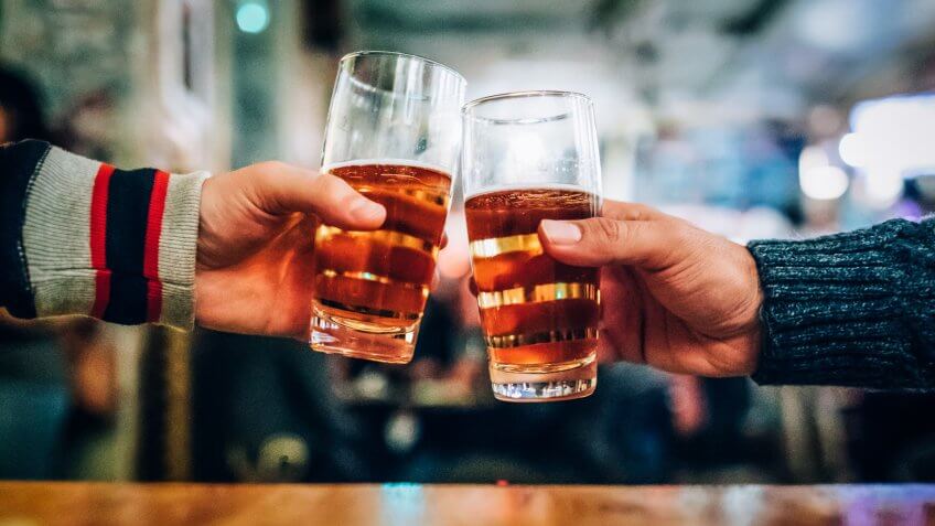friends cheersing at bar with beer