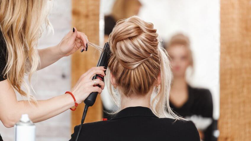 business woman lady boss in beauty salon making hairdress and looking to the mirror.