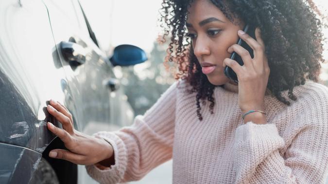 Black oman making a phone call after having a car crash.