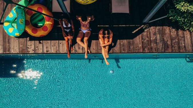 Aerial view of three friends relaxing by the pool.