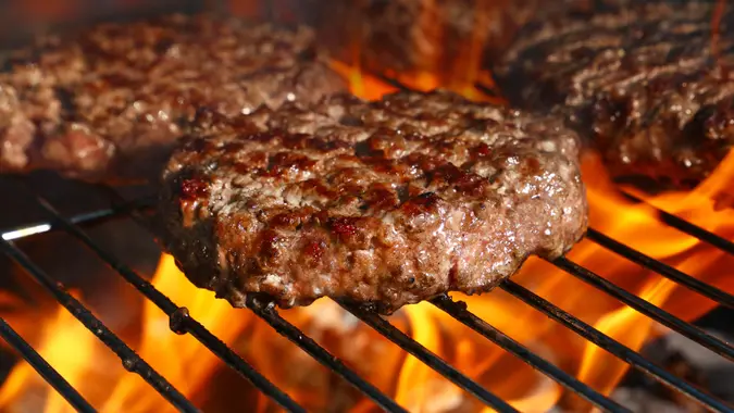 Close up beef or pork meat barbecue burgers for hamburger prepared grilled on bbq fire flame grill, high angle view.