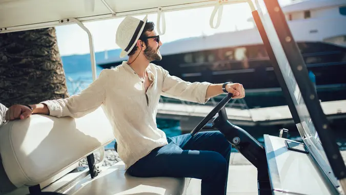 Man driving electric golf car on the dock by the sea.