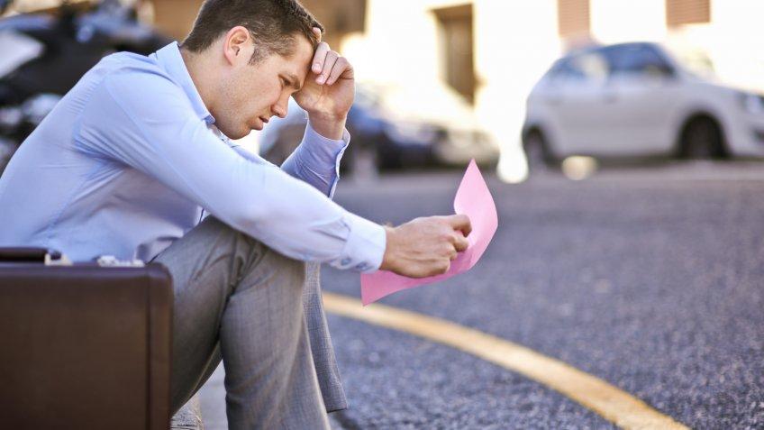 A businessman holding a pink slip terminating his employmenthttp://195.
