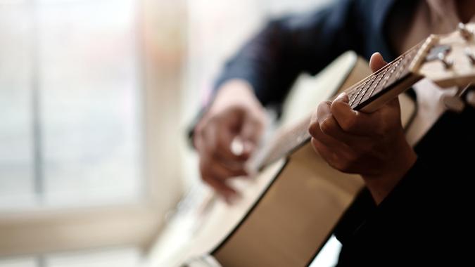 Cropped shot of man practicing in playing acoustic guitar.