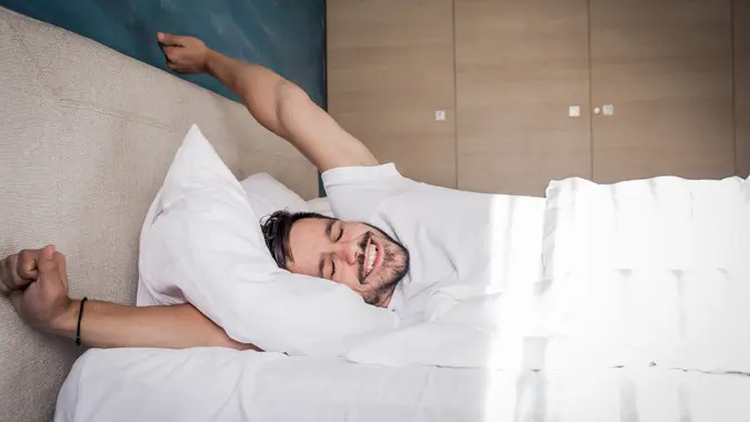 https://cdn.gobankingrates.com/wp-content/uploads/2019/10/guy-waking-up-in-the-morning-iStock-1054282480.jpg?webp=1&w=675&quality=75