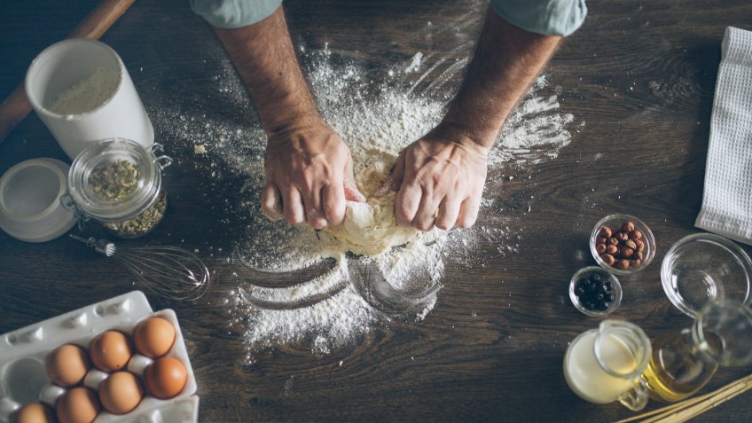 Pastry chef kneading dough in kitchen.