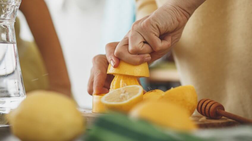 Close-up shot of a woman squeezing juice and making lemonade in the kitchen.