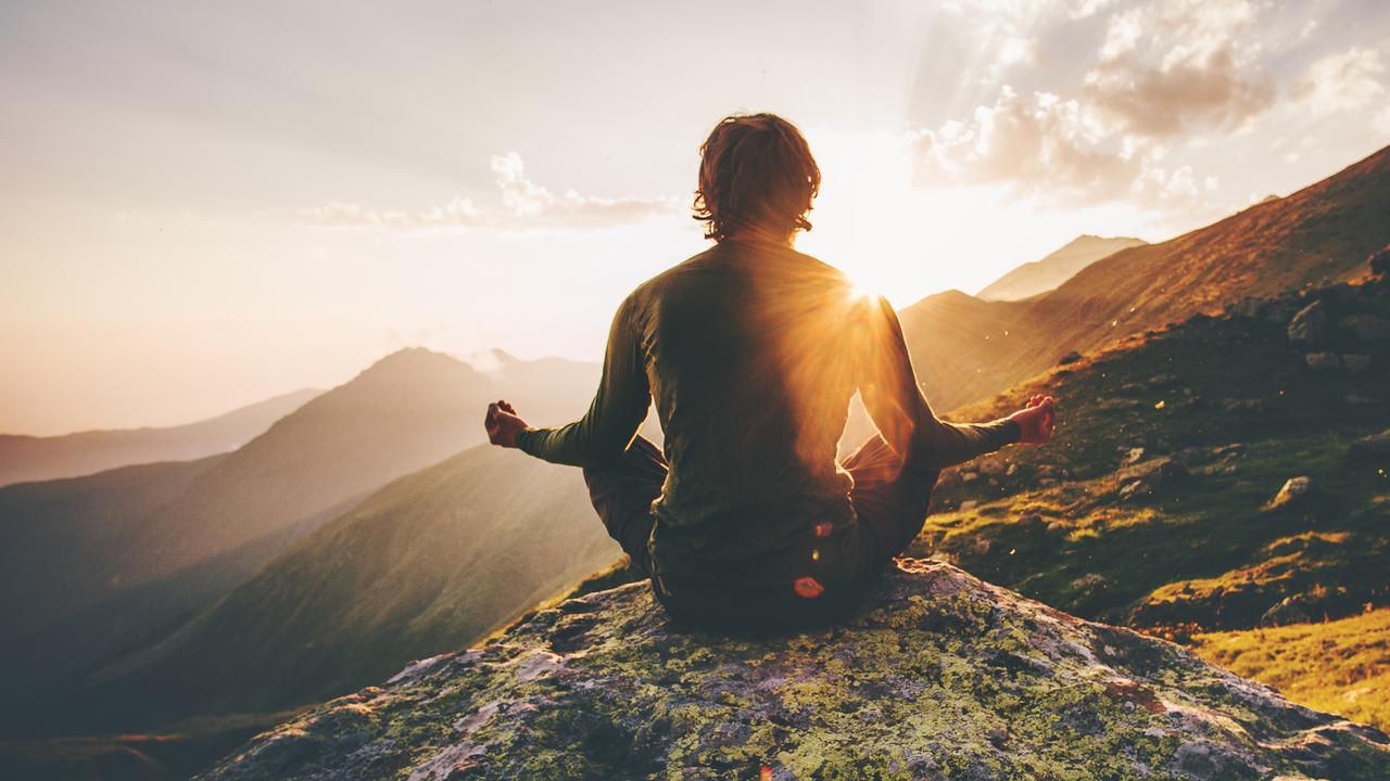 Man meditating yoga at sunset mountains Travel Lifestyle relaxation emotional concept adventure summer vacations outdoor harmony with nature.