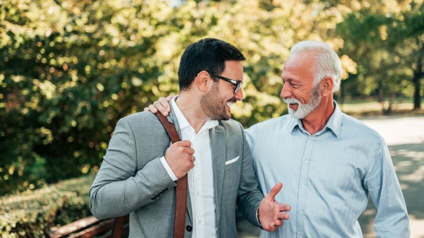 Two friendly businessman walking outdoors.